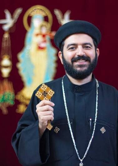 Portrait of Fr. Daniel Nakhla holding a hand cross